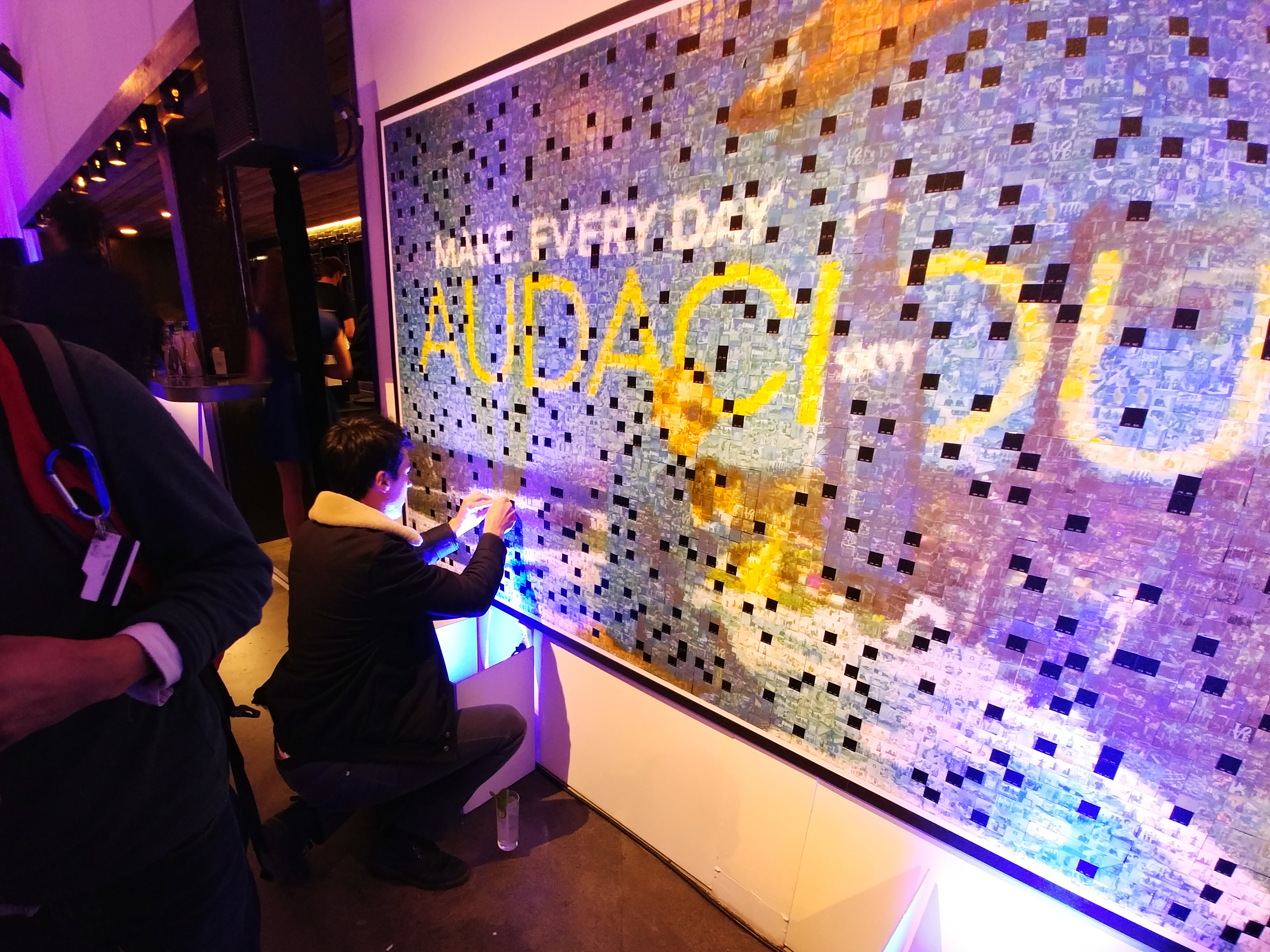 Guest placing a printed tile onto the Skyy and Wired mosaic wall
